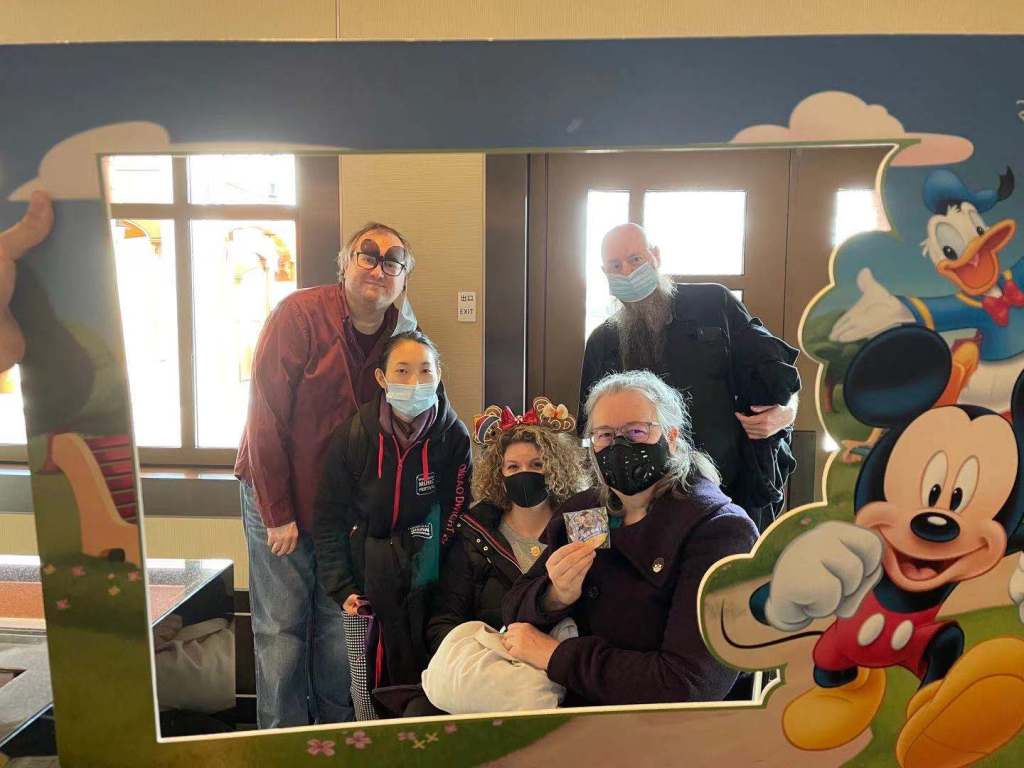 five friends all wearing medical face masks framed by a Disney themed frame
