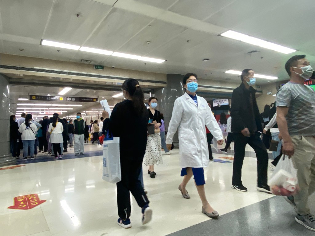 A wide hospital hallway crowded with people on the move.