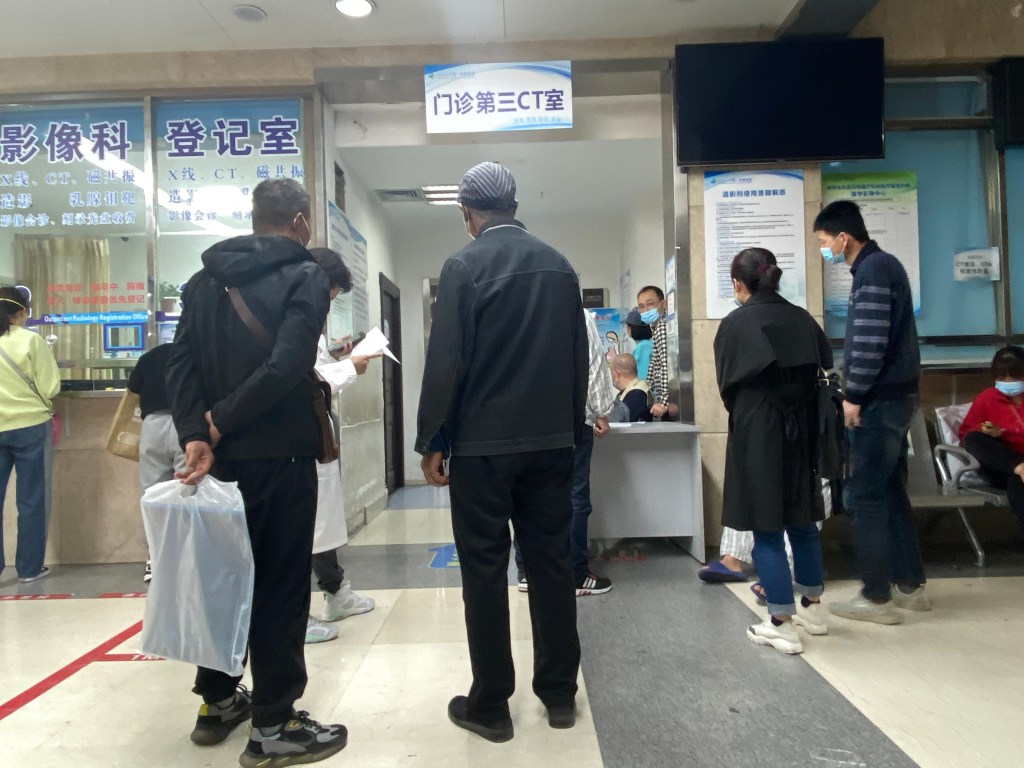 People waiting where there is no waiting area or lobby, just a busy hallway.